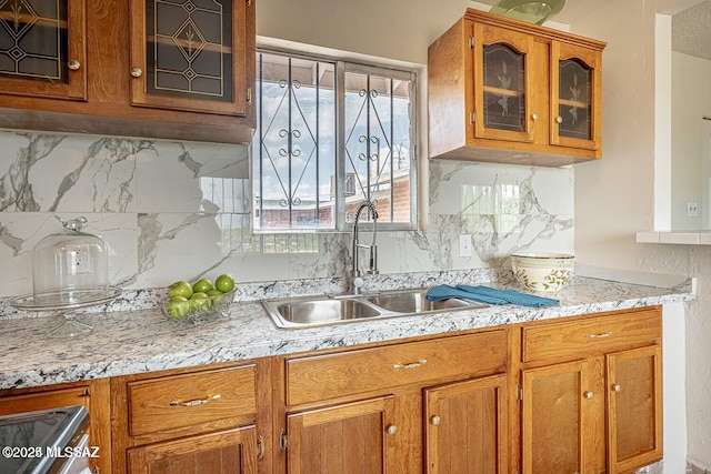 kitchen featuring decorative backsplash, sink, and light stone counters