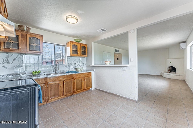 kitchen with range hood, electric stove, a textured ceiling, a tile fireplace, and sink