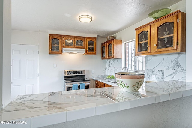 kitchen with electric stove, backsplash, and kitchen peninsula