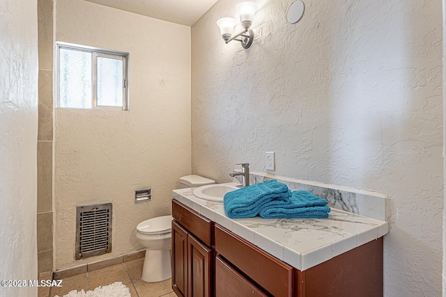 bathroom with toilet, vanity, and tile patterned floors