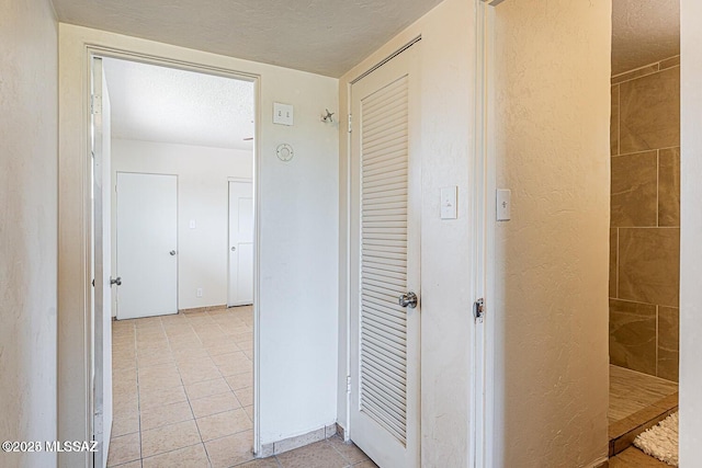 corridor featuring light tile patterned flooring and a textured ceiling