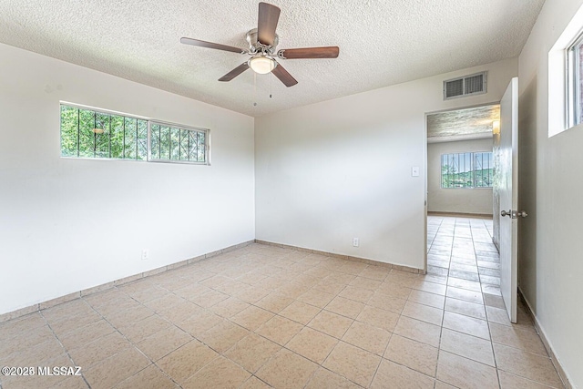 unfurnished room featuring ceiling fan, light tile patterned flooring, and a textured ceiling