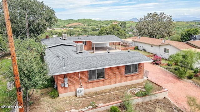 rear view of house featuring central AC unit and a mountain view