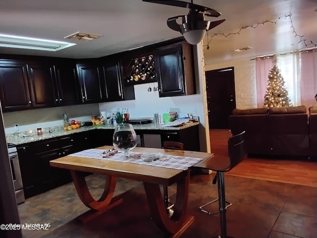 kitchen with ceiling fan, light stone countertops, and range