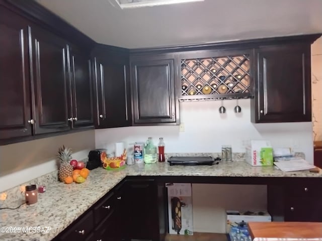 kitchen featuring light stone countertops and dark brown cabinets