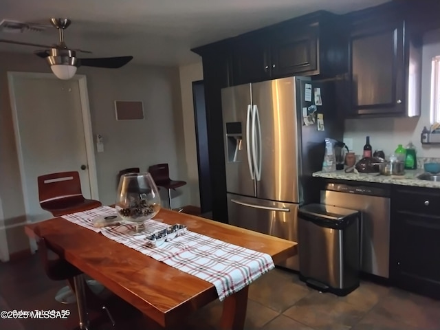 kitchen featuring stainless steel fridge with ice dispenser, ceiling fan, dishwasher, dark tile patterned flooring, and light stone counters