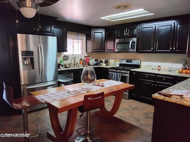 kitchen with light stone countertops, light tile patterned floors, and stainless steel appliances