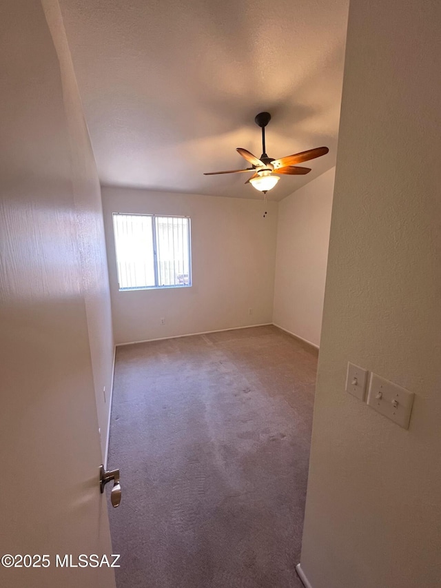 carpeted empty room featuring baseboards and ceiling fan