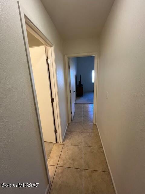 hall with light tile patterned floors and baseboards