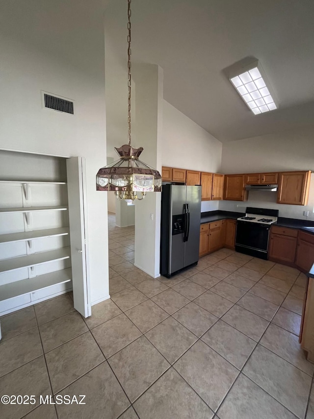 kitchen featuring visible vents, brown cabinets, stainless steel refrigerator with ice dispenser, dark countertops, and gas range oven