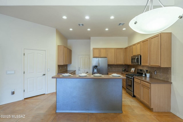 kitchen featuring hanging light fixtures, backsplash, stainless steel appliances, light tile patterned flooring, and light brown cabinets