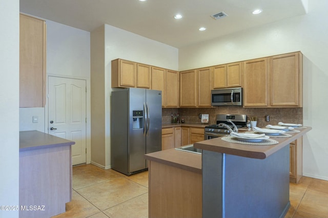 kitchen with light tile patterned floors, a breakfast bar, stainless steel appliances, decorative backsplash, and light brown cabinets