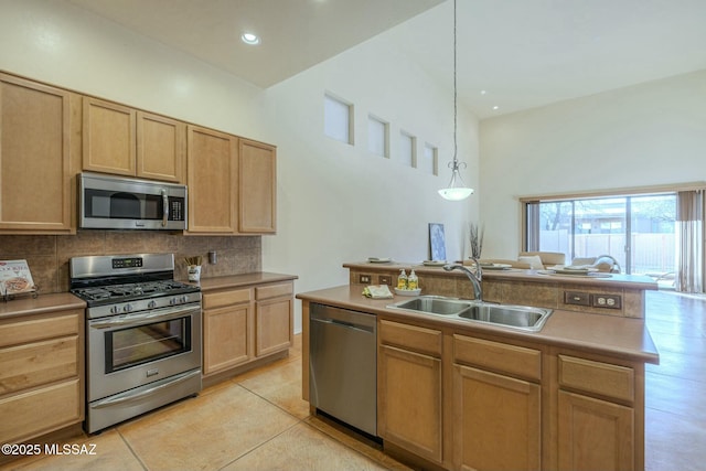 kitchen featuring decorative light fixtures, sink, a kitchen island with sink, light tile patterned floors, and stainless steel appliances