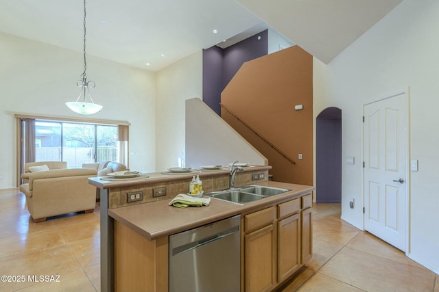 kitchen featuring sink, a high ceiling, a center island with sink, decorative light fixtures, and stainless steel dishwasher