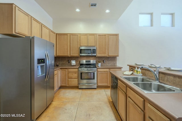 kitchen with light tile patterned flooring, appliances with stainless steel finishes, sink, and light brown cabinets