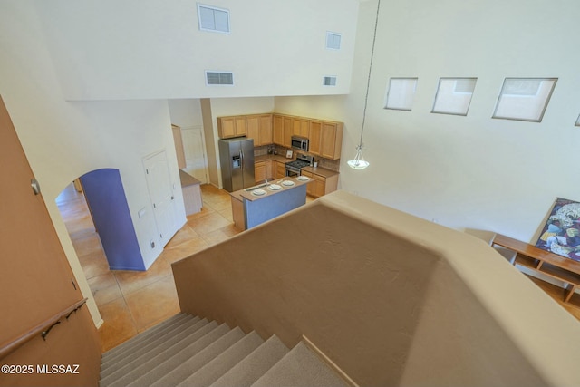 stairway featuring a towering ceiling and tile patterned flooring