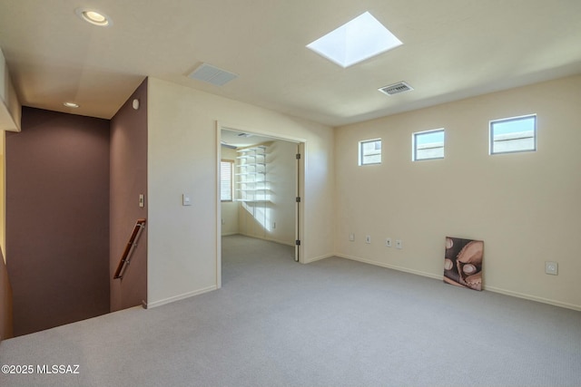 spare room with light carpet, a skylight, and plenty of natural light