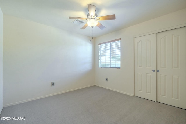 unfurnished bedroom with ceiling fan, light colored carpet, and a closet