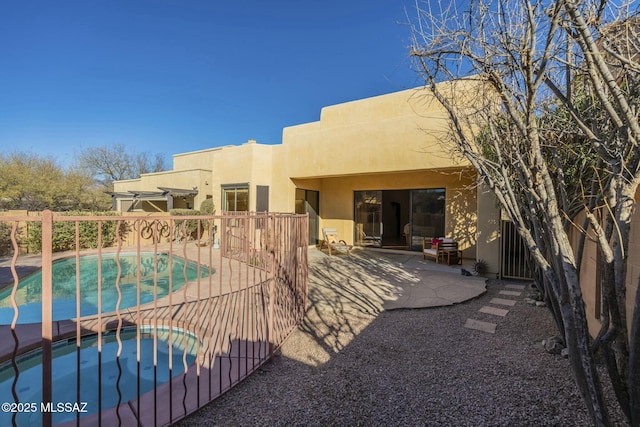 back of property with a pool with hot tub and a patio