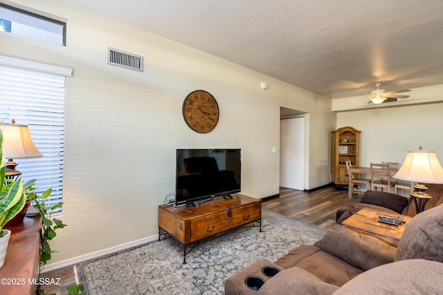 living room featuring ceiling fan, wood finished floors, visible vents, and baseboards