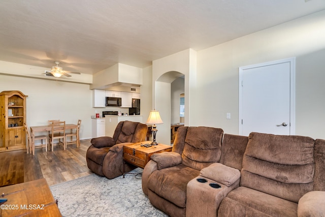 living room with a ceiling fan, arched walkways, and wood finished floors