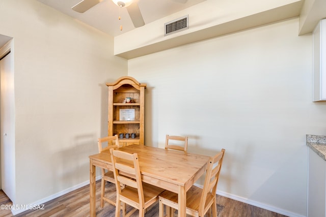 dining room featuring a ceiling fan, wood finished floors, visible vents, and baseboards