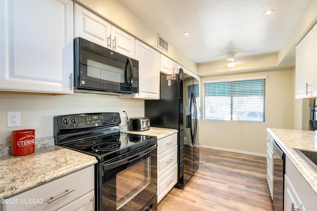 kitchen with visible vents, baseboards, light wood-style flooring, black appliances, and white cabinetry