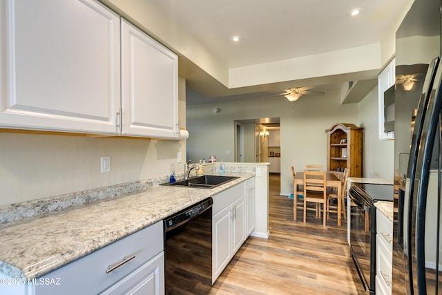 kitchen featuring black appliances, light wood-type flooring, a sink, and white cabinets