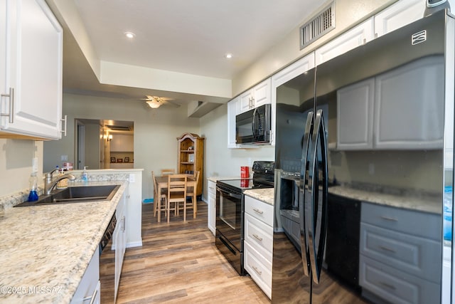 kitchen featuring a sink, visible vents, light wood-style floors, light countertops, and black appliances