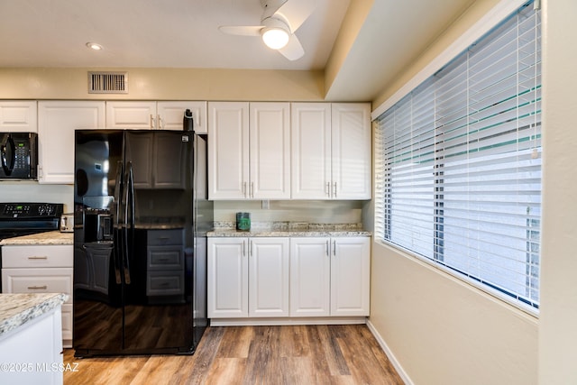 kitchen with light wood-type flooring, visible vents, black appliances, and white cabinetry