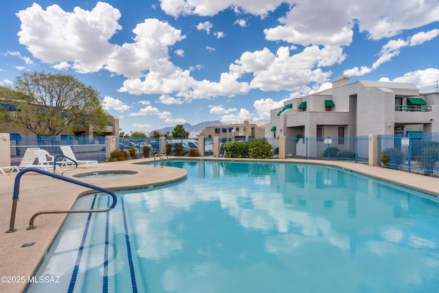 pool featuring fence and a hot tub