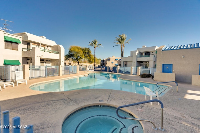 pool featuring a community hot tub, a patio area, fence, and a residential view