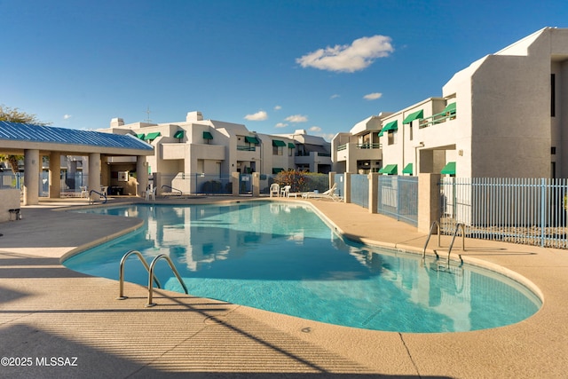 community pool featuring a residential view, fence, and a patio