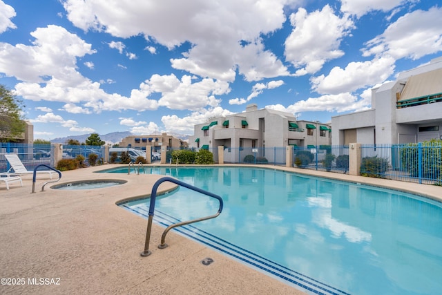 community pool with fence, a hot tub, and a patio