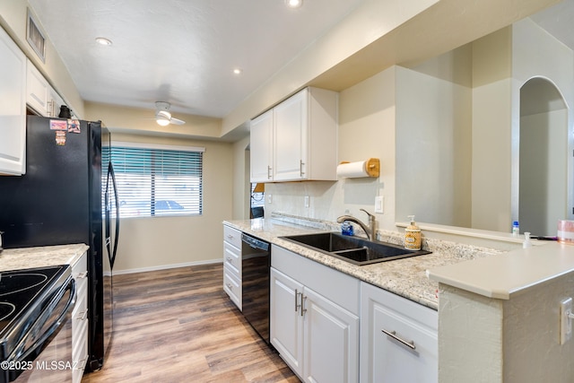 kitchen with black appliances, white cabinetry, visible vents, and a sink