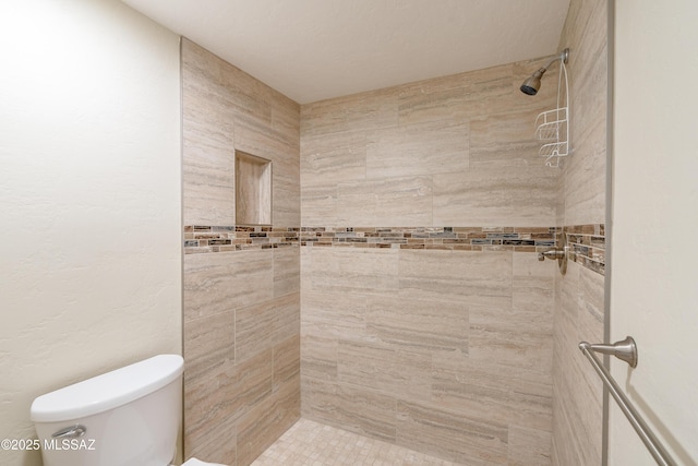 bathroom with toilet and a tile shower