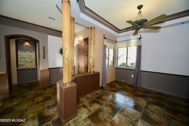 unfurnished room featuring ceiling fan, a raised ceiling, ornamental molding, and ornate columns