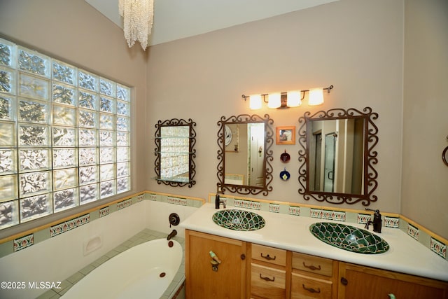 bathroom with a chandelier, a washtub, and vanity