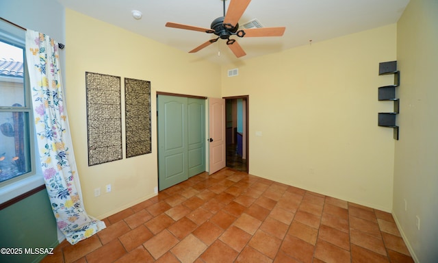 unfurnished bedroom featuring ceiling fan, light tile patterned floors, and a closet