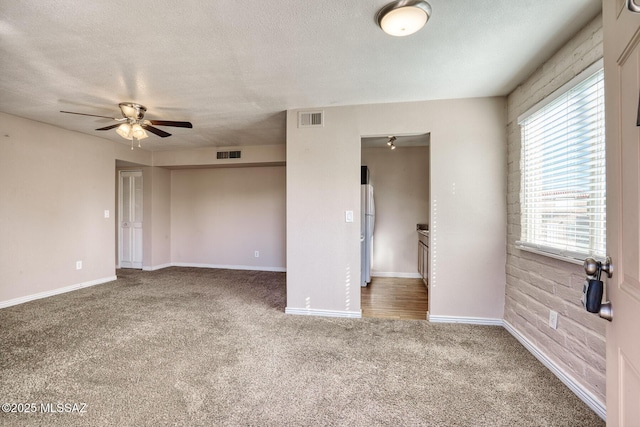 carpeted spare room with ceiling fan and a textured ceiling