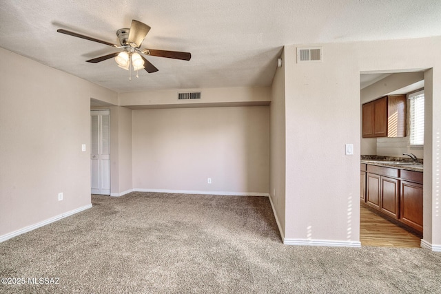 interior space with light carpet, sink, and a textured ceiling