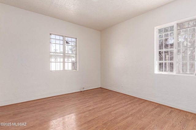 unfurnished room with light hardwood / wood-style flooring and a textured ceiling