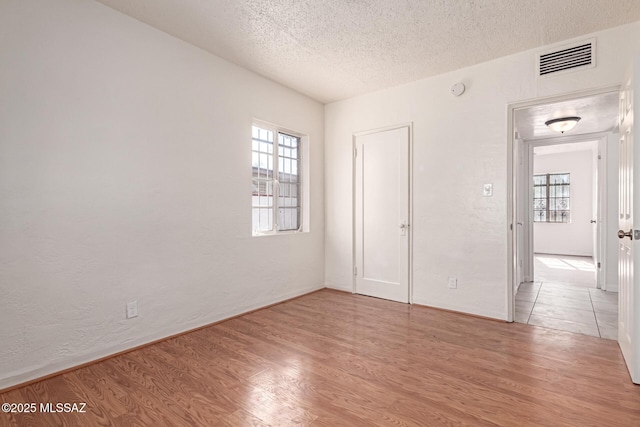 unfurnished bedroom featuring a textured ceiling, light hardwood / wood-style floors, and a closet