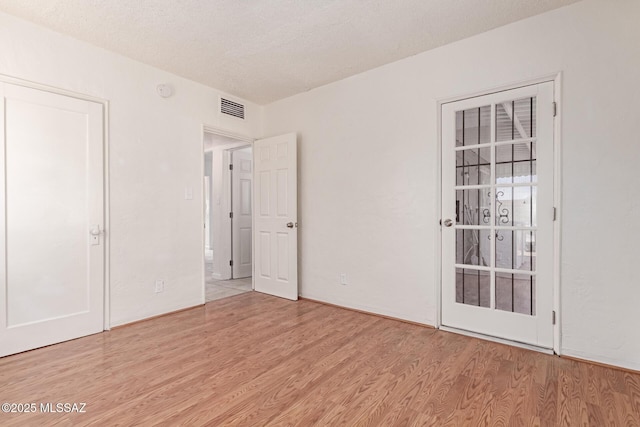 unfurnished bedroom with a textured ceiling and light wood-type flooring