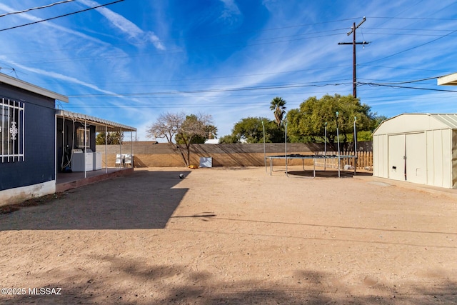 view of yard featuring a storage shed and a trampoline