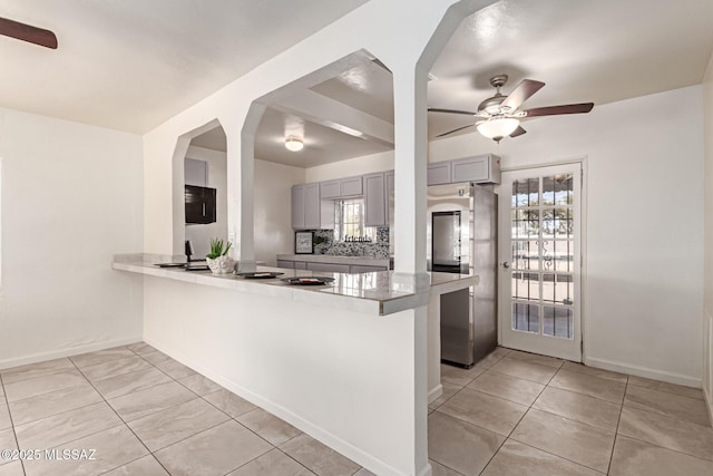 kitchen with gray cabinets, stainless steel refrigerator, light tile patterned floors, ceiling fan, and kitchen peninsula