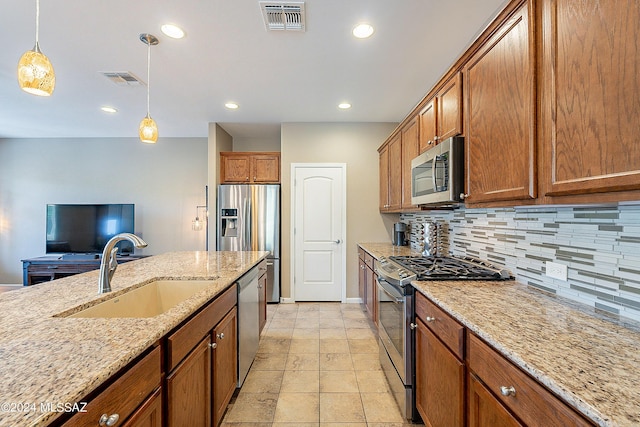 kitchen featuring appliances with stainless steel finishes, sink, decorative light fixtures, backsplash, and light stone counters