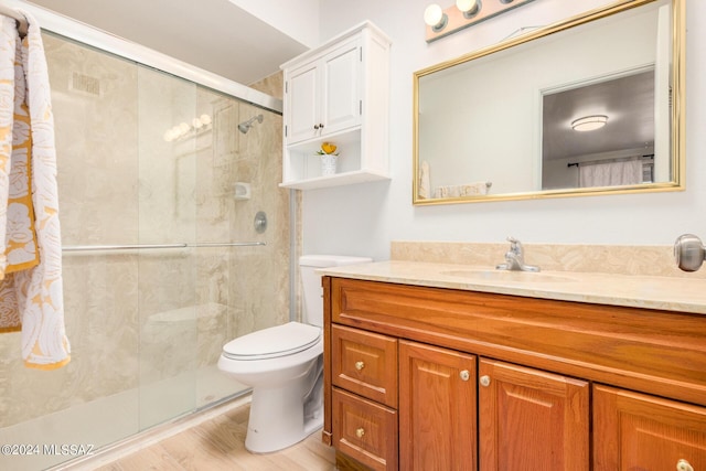 bathroom featuring hardwood / wood-style flooring, vanity, a shower with shower door, and toilet