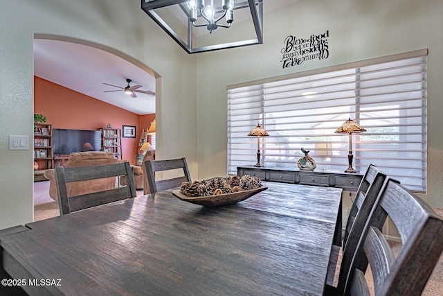 dining space featuring ceiling fan with notable chandelier and vaulted ceiling