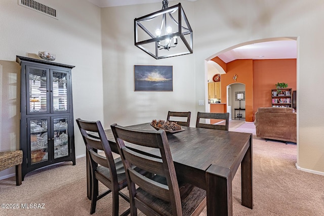 carpeted dining area featuring an inviting chandelier